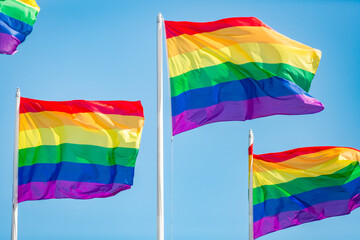 Rainbow flag fluttering against blue sky, Pride LGBT community symbol