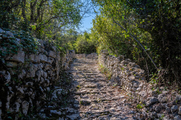 Stony path between dry stone walls around Sauve, Gard, South of France, on a sunny spring afternoon