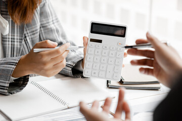 A person holding a white calculator, a group of businessmen in a meeting room discussing and verifying the account numbers in the company's financial statements for accuracy. Business meeting concept.