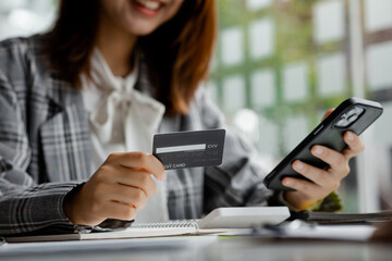 Beautiful woman holding a credit card, she uses a credit card to pay for goods and services online, the concept of using a credit card for online shopping, ordering goods and services on the website.