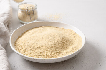 Sesame flour in white bowl for cooking vegan dessert. Good source of protein, minerals, natural antioxidants and vitamins. Close up.