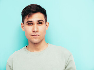 Portrait of handsome smiling stylish hipster lambersexual model.Man dressed in T-shirt and jeans. Fashion male isolated in studio. Posing near blue wall. Cheerful and happy