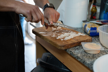 Obraz na płótnie Canvas Chef cutting onion on a wooden board in the kitchen.
