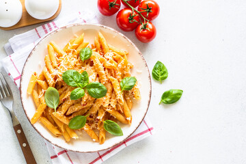 Pasta with tomato sauce, basil and parmesan on white table. Penne pasta with tomato sauce alla arrabbiata. Top view with copy space.