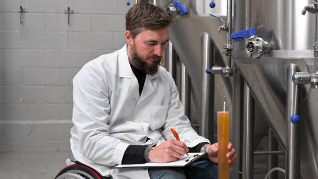 Professional brewmaster controlling craft beer production process in brewery, measuring beverage density with hydrometer. High quality 4k footage