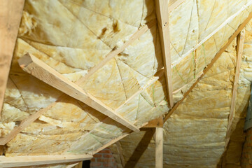 Laying sheet glass wool between roof rafters. Technology and process of insulating the roof of a private house
