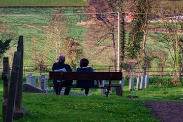 couple sitting on a bench in a cemetery
