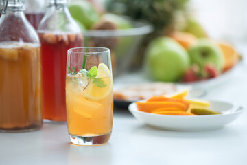 Homemade fermented raw Kombucha tea, healthy natural probiotic flavored drink, glass of Kombucha drink with lemon on white background