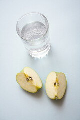 Pieces of apple and a glass of cold water with free copy paste space. Healthy lifestyle and dieting concept still life.