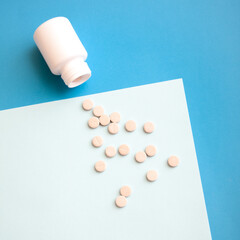 White plastic bottle and pills on blue background