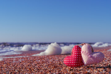 Image of a soft toy in the shape of a heart on the beach.