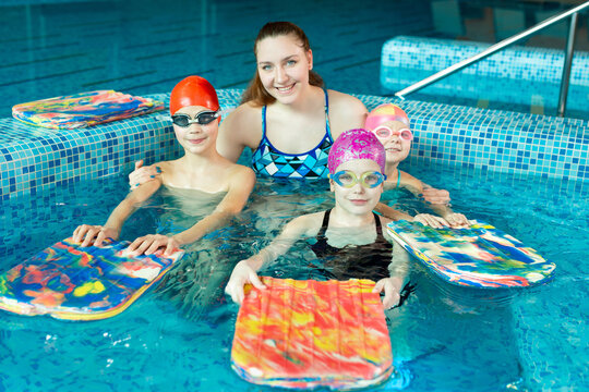 Young girl swimming instructor with children in the pool