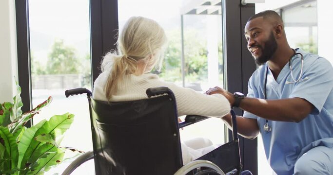 Video of happy african american male doctor taking care of caucasian senior woman