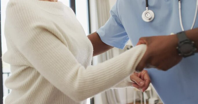 Video of midsection of african american male doctor taking care of caucasian senior woman