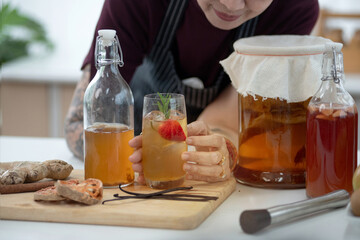 Tattooed woman with Kombucha drink in glass and bottles, dietetic organic superfood healthy fermented tea