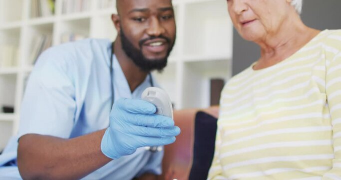 Video of midsection of african american male doctor checking glucose level to caucasian senior woman