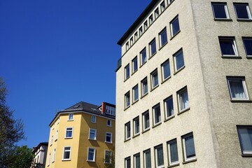 Eckhäuser und Fassaden in der Architektur der Nachkriegszeit in Beige und Naturfarben vor blauem...