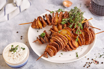 Crispy tornado potatoes. Potato chips on skewers, roasted with thyme and spices. Delicious snack served with sauce. Fast food.