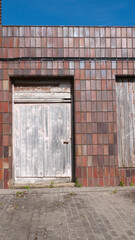 Fototapeta na wymiar Puerta de madera vieja en fachada de baldosa marrón
