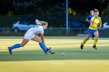 Young girl lead the ball in attack during field hockey game.