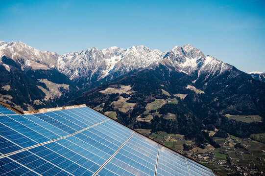 Dach mit Photovoltaik bei Sonnenschein, hoch in den Bergen. Solaranlage, im Hintergrund schneebedeckte Berge in S&uuml;dtirol