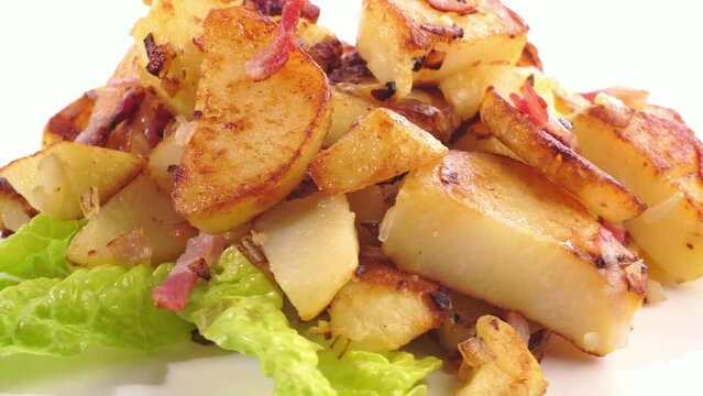 Bratkartoffeln mit Speck, Zwiebeln und Basilikum freigestellt auf wei&szlig;em Hintergrund