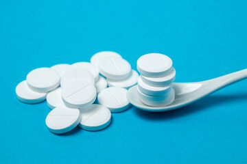 White pills on a blue background. Prevention and treatment with pills. Vitamin tablets