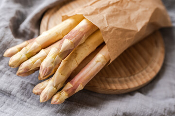 white asparagus in craft paper on a cutting board