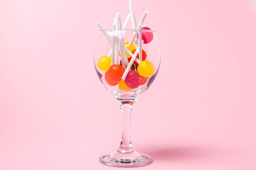 Lollipops in a glass on a pink background. Various fruit candies. sweet treat