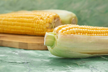 Yellow raw corn cobs on wooden board on table. Watercolor green background. food, vegetarianism....