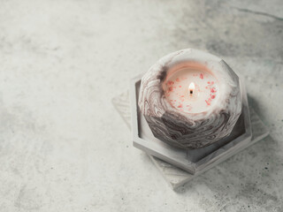Soy candle in a concrete, plaster candlestick, decor interior. Home decoration with a burning scented candle. Spa. Natural.