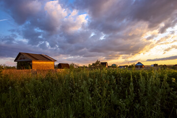 Summer village landscape at sunset with an old wooden house.
