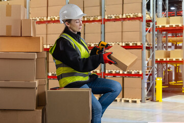 A woman scans barcode on package. Warehouse worker holding cardboard box. Data collection terminal in hands of woman. Warehouse technology concept. Female is in industrial warehouse.