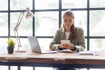 Business asian woman using smartphone for do math finance on wooden desk in office, tax, accounting, financial concept