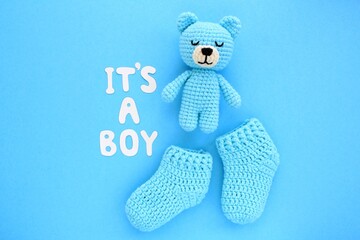 It's a boy lettering, crochet bear and baby booties on blue background. Baby boy birth, new life,...