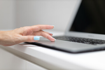 female hand presses a finger on the touchpad surface of a laptop