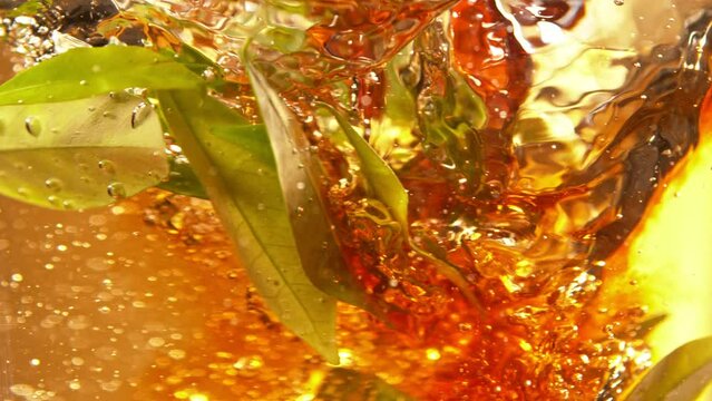 Super Slow Motion Shot of Pouring Tea into Whirl with Green Leaves at 1000fps.