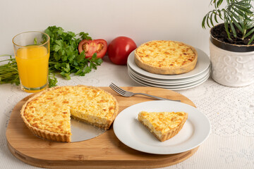 Cheese quiche, a pie on a wooden board, a slice of the pie on a white plate