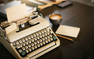 Old typewriter on wooden table with note book and coffee drink, desk office of writer, retro style...