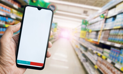 Close up view, hand holding smart phone with blank screen and basket icon and message icon  on bottom, Blurred products in shelf on background