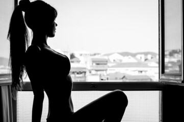 Silueta de perfil de mujer mirando al horizonte por la ventana