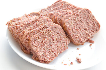 Canned corned beef slices on a white plate.