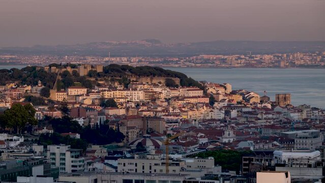 Sunset to night time lapse view of the skyline of Lisbon, Portugal, with the castle and the famous Alfama district