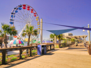 A seaside beach boardwalk with a Ferris wheel under a purple sky. - obrazy, fototapety, plakaty