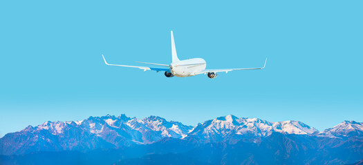 Fototapeta premium Airplane is flying in the sky over mountains with pine forest -Amazing landscape with passenger airplane