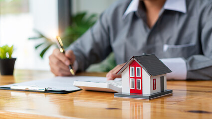 Businessmen holding pens, signing home titles with insurance, care about real estate services and the idea of real estate agents offering interest in installments to their customers.