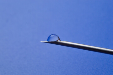 Syringe needle and a drop of a transparent substance. close-up