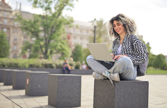 young woman uses a computer in a park