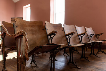 The worn and weathered old pews of a church are visible in a well-lit room