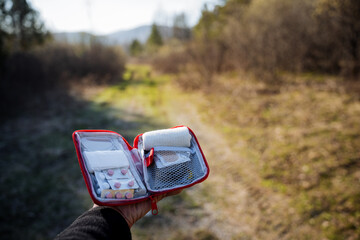 A first-aid kit with medicines against the background of the forest, a person's hand holds a bag...